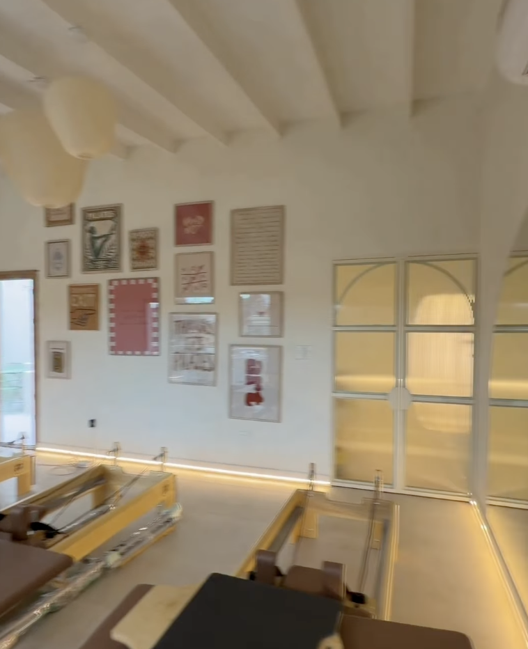 Interior del estudio de Pilates de Equipo Siniger, con reformers y galería de cuadros en la pared